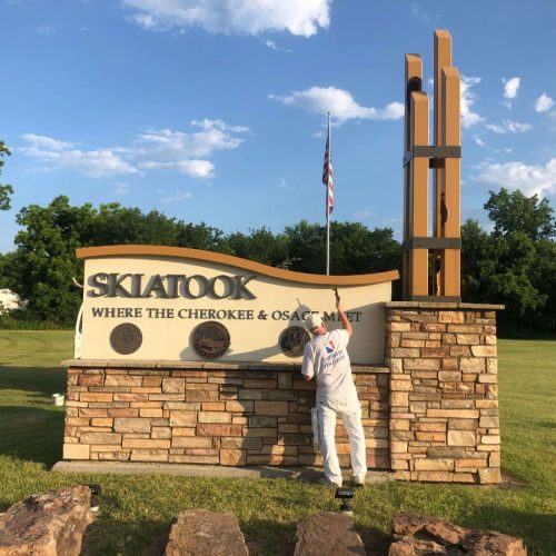Painter working on Skiatook welcome sign outdoors